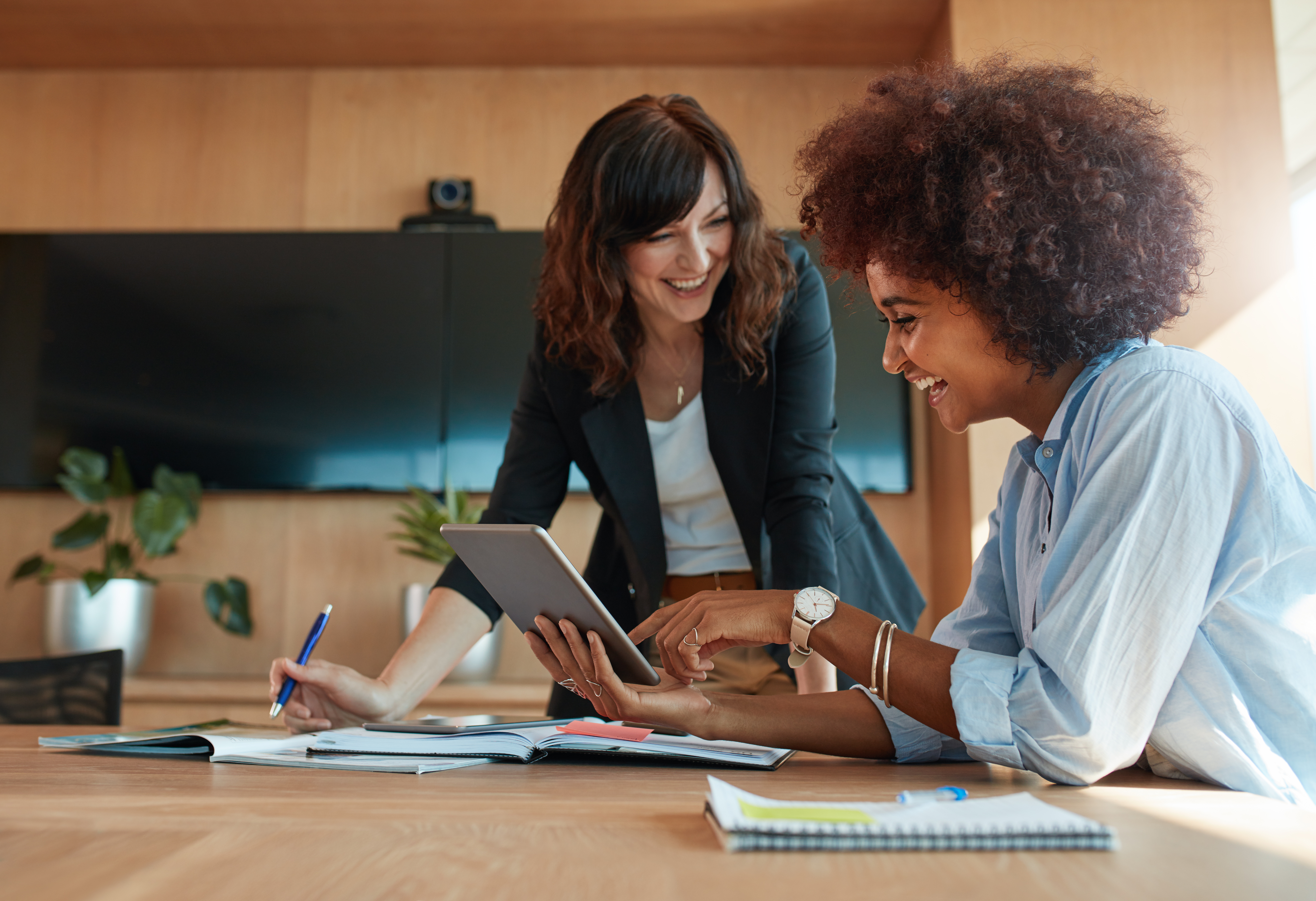 Shot of two young woman working together on digital tablet. Creative female executives meeting in a office using tablet pc and smiling.